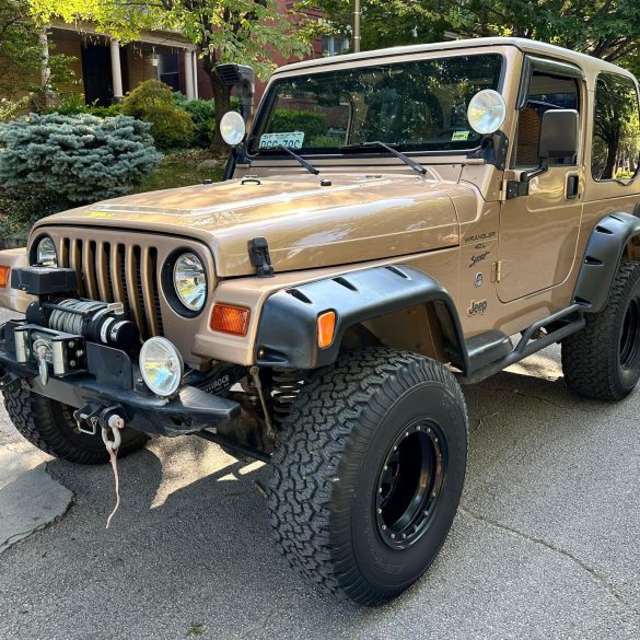 Three-quarter front view of a 1999 gold Jeep Wrangler Sport 4x4
